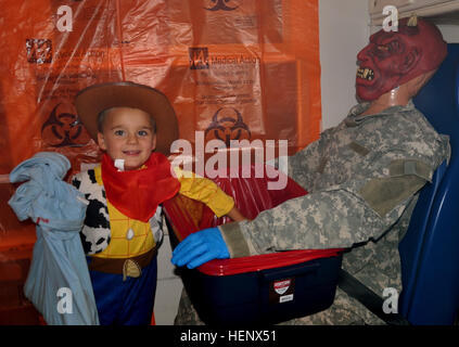Sullivan, 5, dressed as 'Woody' from “Toy Story,” shows no fear as he snags candy from the devilish figure in the Haunted Ambulance during the 402nd Field Artillery Brigade and 5th Armored Brigade, First Army Division West, first of planned annual co-hosted Trunk-or-Treats on Fort Bliss, Texas, Friday. The brigades organized the event in their parking lot to bring Soldiers and their families closer together and allow the children to enjoy a “spooktacular-filled” evening. (Photo by Capt. Olivia Cobiskey, 402nd Field Artillery Brigade, First Army Division West Public Affairs) Fort Bliss Trunk or Stock Photo