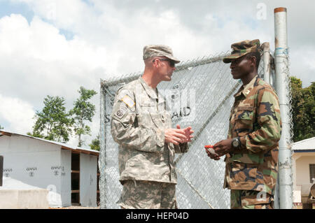 In this file photo, Lt. Col. Michael Baker, left, commander of the 62nd Engineer Battalion, 36th Engineer Brigade, speaks with Armed Forces of Liberia Capt. Abraham Kamara, the deputy project officer for the Sinje ETU site Nov. 19, 2014. Baker’s Soldiers helped build 10 Ebola treatment units throughout Liberia. The 62nd Eng. Bde. has completed its mission and is scheduled to observe this by casing its colors Feb. 2, 2015. Operation United Assistance is a Department of Defense operation in Liberia to provide logistics, training and engineering support to U.S. Agency for International Developmen Stock Photo