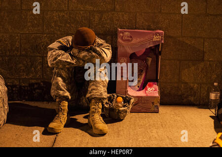 Paratroopers line the street before the sun rises, waiting to donate their toys in hopes of receiving a winning lottery ticket for the opportunity to earn foreign jump wings at the 17th Annual Randy Oler Memorial Operation Toy Drop. The airborne operation is hosted by the U.S. Army Civil Affairs & Psychological Operations Command (Airborne), a U.S. Army Reserve operational command, Dec. 5, 2014 at Pope Field, N.C. Operation Toy Drop is the world’s largest combined airborne operation with seven allied partner nation paratroopers participating and allows Soldiers the opportunity to help children Stock Photo