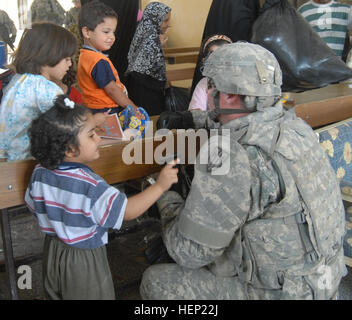 Staff Sgt. Joseph Reinsburrow, 64th Military Police Company, who is a native of Towanda, Pa., interacts with the children of Hurriyah on June 12 as Iraqi police and Multi-National Division - Baghdad Soldiers hand out toys and school supplies to the local children. The 64th MP Co. is deployed from Fort Hood, Texas, and is currently assigned to the 716th MP Battalion, 18th MP Bde., MND-B. IP making difference in local Baghdad community 94493 Stock Photo