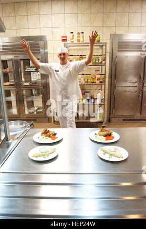 After hearing a grader yell 'hands up,' Sgt. Kory Bender, Alpha Company, 40th Expeditionary Signal Battalion, 11th Signal Brigade, throws his hands up and steps away from his dishes. During the Culinary Arts Noncommissioned Officer of the Year board at Fort Hood, Texas, Jan. 8–9, Soldiers needed to have completed plating their meals and have them ready for presentation when that command was given. (U.S. Army Photo by Staff Sgt. Kelvin Ringold) Sergeant cooks up a win at Culinary Arts of Quarter board 150109-A-HT688-316 Stock Photo