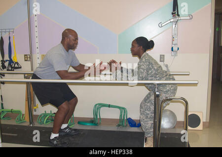 Sgt. Latonya Sharp, a physical therapy technician at Madigan Army Medical Center on Joint Base Lewis-McChord shows Master Sgt. Marvin Howard, a mechanical maintenance supervisor, with the Warrior Transition Battalion, the correct way to perform one of his many exercises during his physical therapy session, Jan. 20, 2015.  It has been three months since Howard underwent a total knee replacement surgery and he said Sharp has helped him mentally and physically to get to this stage in his recovery. Madigan Soldier motivates patients through compassion, commitment 150120-A-RT214-002 Stock Photo
