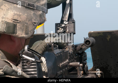 Sgt. Douglas Henry, from Strausburg, Pennsylvania, a watercraft operator aboard the U.S. Army Vessel Corinth, holds the M240B machine gun steady as rounds are loaded in preparation to fire as a part of wet range for weapons familiarization for vessel defense in training area “Hotbox Charlie” in Kuwait Bay, Feb. 9. (U.S. Army photo by Staff Sgt. Gene Arnold, 7th Mobile Public Affairs Detachment) Not your average battleship 150209-A-MX893-007 Stock Photo