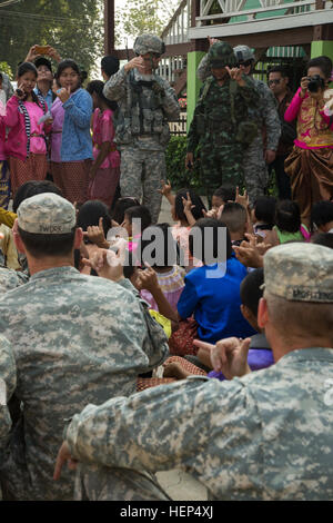 U.S. Army Lt. Col. Neal Mayo, commander of 1st Battalion, 27th Infantry Regiment, 2nd BCT, 25th Infantry Division, and fellow 25ID soldiers exchange Hawaiian Shaka gestures meaning 'Aloha' or a general 'hello, goodbye, good will' with local Thai school children after spending the afternoon with them during a humanitarian aid mission in Lopburi province, Thailand, Feb. 16, 2015. The mission was carried out as a part of the joint-training operation Cobra Gold 2015. (U.S. Army photo by Spc. Steven Hitchcock/Released) Cobra Gold 2015 150216-A-SE706-192 Stock Photo