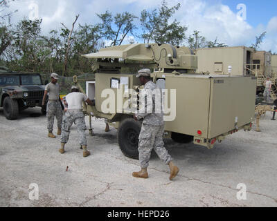 Army Spc. Paul Latimer (left) from Battery D, 2nd Air Defense Artillery Regiment and Sgt. Jarius Bruce (middle) and Spc. Brandon Fuller (right), both from the 307th Signal Battalion emplace communications equipment after the passing of Typhoon Dolphin. The strong storms that strike Guam can be destructive, but it will never break the confidence Task Force Talon Soldiers have in their training and the support from the joint community on Andersen Air Force Base, Guam. (U.S. Army photo by Maj. Jonathan Stafford, executive officer, Task Force Talon, 94th Army Air and Missile Defense Command) Power Stock Photo