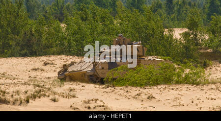 An M2 Bradley Fighting Vehicle belonging to Team Eagle, Task Force 2-7 Infantry, stands guard over the battlefield at the Great Lithuanian Hetman Jonusas Radvila Training Regiment, in Rukla, Lithuania, during a multinational exercise that involved a bombing run by two A-10C Thunderbolt IIs from the 175th Wing, Maryland Air National Guard are based at Ämari Air Base, June 12, 2015. Saber Strike is a long-standing U.S. Army Europe-led cooperative training exercise. This year’s exercise objectives facilitate cooperation amongst the U.S., Estonia, Latvia, Lithuania, and Poland to improve joint ope Stock Photo