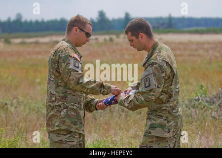 United States Army Chief Warrant Officer 2 Keith Rames, right, a native of Milwaukee, Wis., helps Chief Warrant Officer 2 Chad Remala, a native of Victor, Idaho, both assigned to A Company, 2-159th Attack Reconnaissance Battalion, 12th Combat Aviation Brigade, stationed at Katterbach, Germany, fold a an American flag prior to terrain association and flight training with their Apache A-64 Longbow helicopter at the Great Lithuanian Hetman Jonusas Radvila Training Regiment, in Rukla, Lithuania, June 13, 2015, as part of Saber Strike 2015. Saber Strike is a long-standing U.S. Army Europe-led coope Stock Photo