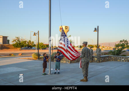 Connor Montague (left) and Jheriko Watson (middle), two Cub Scouts from Pack 8 of El Paso’s Boy Scouts of America, along with Spc. Samuel Montague (right), an AH-64, Apache helicopter, armament/electrical/avionics systems repairer from 1st Armored Division’s Combat Aviation Brigade, prepare to raise the flag as “To The Colors” plays signifying the start of the duty for the Iron Eagles on Fort Bliss, Texas, Monday, June 22, 2015. (U.S. Army photo by Sgt. Jose Ramirez, Combat Aviation Brigade Public Affairs, 1st Armored Division) Cub Scouts visit the CAB 150622-A-AG877-391 Stock Photo