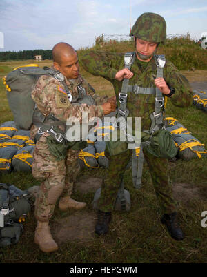 Unites States Army Sgt. 1st Class Angel Nicanor, left, a Miami, Fla., native assigned to Dog Company, 1st Battalion (Airborne), 503rd Infantry Regiment, 173rd Infantry Brigade Combat Team (Airborne), assists Lithuanian Land Forces Pvt. Vidas Balezentis, a paratrooper assigned to Algirdo Battalion, with the fitting of his T-11 parachute during a multinational exercise culminating in a Foreign Jump Wings ceremony at the Great Lithuanian Hetman Jonusas Radvila Training Regiment, in Rukla, Lithuania, July 7, 2015. The Soldiers of Dog Company currently fall under the 4th Infantry Division Mission C Stock Photo