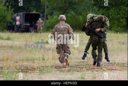 U.S. Army Pfc. Caleb Holloway, left, an infantryman and native of Follett, Texas, assigned to Dog Company, 1st Battalion (Airborne), 503rd Infantry Regiment, 173rd Infantry Brigade Combat Team (Airborne), runs alongside Lithuanian Land Forces Pvt. Andrius Janciulis, right, assigned to Algirdo Battalion, Iron Wolf Brigade as Janciulis carries a wounded LLF Soldier to a waiting U.S. M997 High Mobility Multi-purpose Wheeled Vehicle outfitted as a field ambulance during a medical evacuation training exercise at the Lithuanian Grand Duke Gediminas Staff Battalion in Alytus, Lithuania, July 9, 2015. Stock Photo