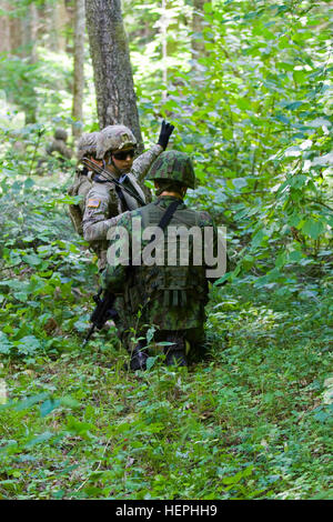 U.S. Army Spc. Sean Jannicelli-Broda, center, assigned to Dog Company, 1st Battalion (Airborne), 503rd Infantry Regiment, 173rd Infantry Brigade Combat Team (Airborne), a native of Souderton, Pa., communicates the enemy’s possible position to Lithuanian Land Forces Lt. Arvydas Lukosevicius, 2nd Platoon Leader for 2nd Coy, Grand Duke Birute Uhlan Battalion and a native of Vilnius, during a bilateral, tactical exercise at the Lithuanian Grand Duke Gediminas Staff Battalion in Alytus, Lithuania, July 16, 2015. The Soldiers of Dog Company are in Europe as part of Atlantic Resolve, a demonstration  Stock Photo