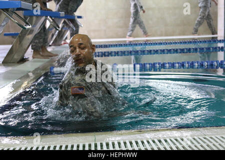 U.S. Army Sgt. 1st Class Greg Whitaker, a North Carolina National Guard Soldier assigned to Multinational Battle Group-East, dives into the pool in his army combat uniform as he participates in the swim portion of the German Armed Forces Proficiency Badge July 28, 2015, at the Step Sport Center in Pristina, Kosovo. To earn the badge, Soldiers must complete the 100-meter swim while wearing their full duty uniform in under four minutes, and also compete in events testing their marksmanship, physical fitness and ruck march endurance. (U.S. Army photo by Ardian Nrecaj, Multinational Battle Group-E Stock Photo