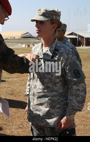 U.S. Army North Carolina National Guard Soldier Major Karen Schlobohm, a senior logistics officer from the 30th Armored Brigade Combat Team, assigned to Multinational Battle Group-East, is awarded the German Armed Forces Proficiency Badge Sept. 13, 2015, at Camp Bondsteel, Kosovo. To earn the badge, Soldiers must complete in the 100-meter swim while wearing their full duty uniform in under four minutes, and also compete in events testing their marksmanship, physical fitness and ruck march for endurance. Conducting joint training with other multinational forces while deployed to Kosovo, establi Stock Photo