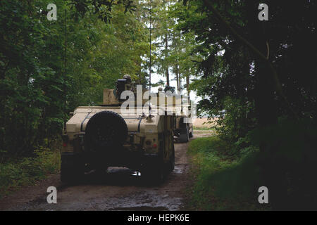 U.S. Army Soldiers assigned to Dog Company, 1st Battalion, 503rd Infantry Regiment, 173rd Airborne Brigade, hide their vehicles along a heavily shaded road from notional in-direct mortar fire during Exercise King Strike had in the town of Panevezys, Lithuania, Sept. 22, 2015. The bilateral exercise involved the 173rd Airborne Brigade’s NATO allies, Lithuanian Land Forces King Mindaugas Hussar Battalion (KMHB), who role-played oppositional forces during the 72-hour exercise. This training event will improve both countries’ ability to operate as a combined force, which increases NATO’s ability t Stock Photo