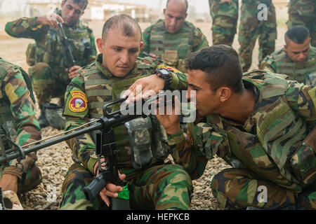 An Iraqi soldier assigned to 1st Battalion, 71st Iraqi Army Brigade inspects another soldier's weapon during a preliminary marksmanship instruction class at Camp Taji, Iraq, Oct. 5, 2015. The Iraqi soldiers were in the beginning stages of learning how to safely handle and operate an M16 rifle. Task Group Taji are part of the coalition of regional and international nations that have joined together to defeat the Islamic State in Iraq and the Levant and the threat they pose to Iraq, Syria, the region and the wider international community. (U.S. Army photo by Spc. William Marlow/Released) M16 rif Stock Photo