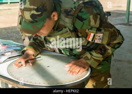 An Iraqi soldier assigned to the 71st Iraqi Army Brigade plots coordinates on a map during mortar training at Camp Taji, Iraq, Nov. 4, 2015. The soldier learned how to plot the coordinates to assist with indirect fire attacks against the Islamic State of Iraq and the Levant (ISIL). The training is provided by the Iraqi Train and Equip Fund and will assist in setting up fire direction center during battles against ISIL. (U.S. Army photo by Spc. William Marlow/Released) Iraqi soldiers take part in mortar, urban operations training at Camp Taji, Iraq 151104-A-OB785-016 Stock Photo