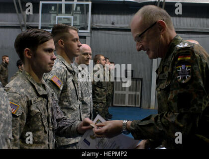 U.S. Army Spc. Joseph Gay, an Alabama National Guard explosive ordnance disposal technician serving in Kosovo with Multinational Battle Group-East, accepts the German Armed Forces Proficiency Badge from German Col. Hans-Jürgen Freiherr von Keyserlingk, commander for the German contingent in Kosovo, Dec. 29, 2015, at Camp Bondsteel, Kosovo. In order to earn the badge, Soldiers completed a 100-meter swim while wearing their full duty uniform, a ruck march, and other events testing their marksmanship and physical fitness. (U.S. Army photo by Sgt. Erick Yates, Multinational Battle Group-East) US S Stock Photo