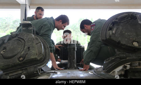 Slovenian soldiers of 45th Center for Tracked Combat Vehicles (CGBV) attach Multiple Integrated Laser Engagement Systems (MILES) components onto an M-84 main battle tank during Swift Response 16 training exercise at the Hohenfels Training Area, a part of the Joint Multinational Readiness Center, in Hohenfels, Germany, Jun. 8, 2016. Exercise Swift Response is one of the premier military crisis response training events for multi-national airborne forces in the world. The exercise is designed to enhance the readiness of the combat core of the U.S. Global Response Force – currently the 82nd Airbor Stock Photo