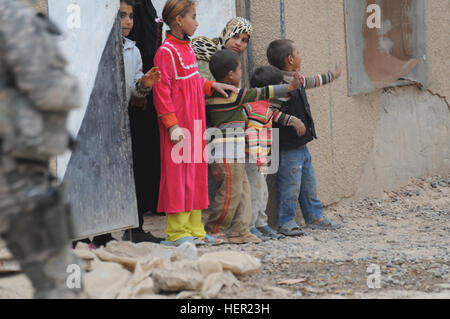 Iraqi children from Al Delami, south of Baghdad, wave to U.S. Soldiers from Bravo Company, 2nd Battalion, 6th Infantry Regiment, 2nd Brigade Combat team, 1st Armored Division patrols by on Nov. 20. Patrol in Al Delami 131071 Stock Photo