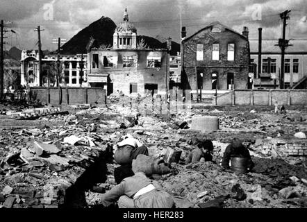 Korean women and children search the rubble of Seoul for anything that can be used or burned as fuel.  November 1, 1950.  Capt. F. L. Scheiber. (Army) NARA FILE #:  111-SC-351697 WAR & CONFLICT BOOK #:  1503 SeoulWarDamage1 Stock Photo