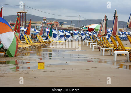 Rainbow colored beach umbrellas in rows on a beach in Crete Stock Photo