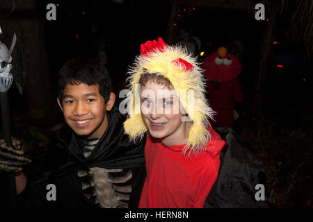 Asian American young teen in Halloween skeleton costume & white pal in yellow wig trick or treating. St Paul Minnesota MN USA Stock Photo