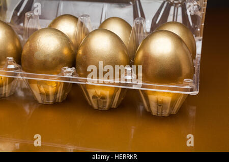 Golden eggs in a plastic box on golden background Stock Photo