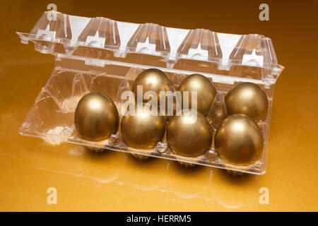 Golden eggs in a plastic box on golden background Stock Photo