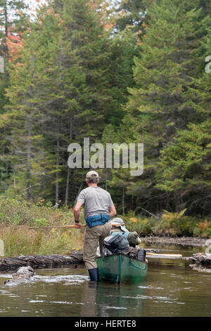 Stepping into a canoe in a shallow area on a trip in the St. Regis Canoe Area of Adirondack State Park, New York. Stock Photo