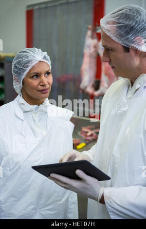 Butchers discussing over digital tablet at meat factory Stock Photo - Alamy