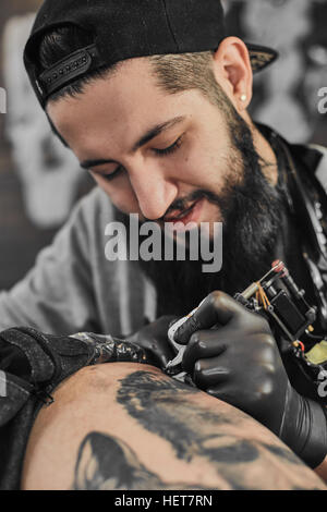 Tattoo master is tattooing in the tattoosalon Stock Photo