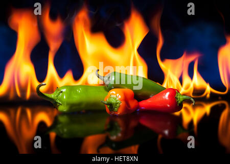 Chili Peppers with fire in the background. Shallow depth of field with focus on the jalapeno. Peppers are on reflective surface. Stock Photo
