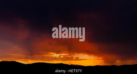 Fiery Sunset with rain on the horizon Stock Photo