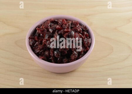 Dried cranberries in pink bowl on wooden table Stock Photo