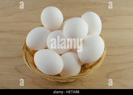 Wooden basket of white chicken eggs on table Stock Photo