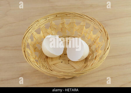 Broken egg shells in wooden basket on table Stock Photo