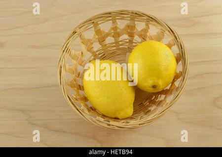 Two raw whole lemons on wooden wicker basket Stock Photo