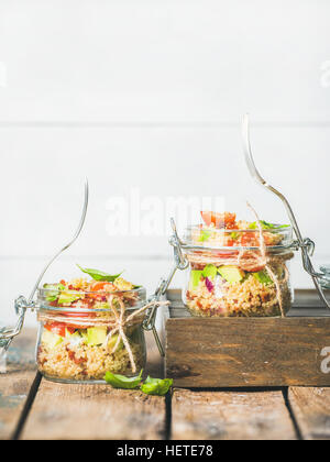 Homemade jar quinoa salad with cherry-tomatoes, avocado and basil leaves Stock Photo