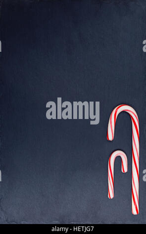 Holiday striped candy canes on dark stone background. Top view, flat lay. Stock Photo
