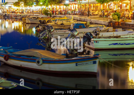 AGIOS NIKOLAOS, CRETE - JULY 26, 2012: Tourists relax in outdoor restaurant on the shores of lake Voulismeni with a lot of boats Stock Photo