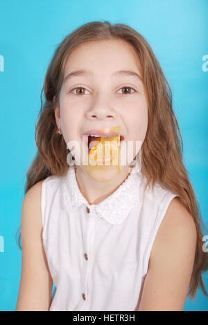 Young girl playing with chewing gum isolated on blue Stock Photo