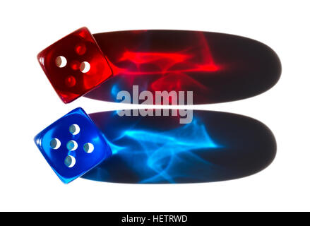 Two tiny translucent plastic dice with long shadows. Red and blue dice in sunlight with shiny colorful shadow cones. Stock Photo