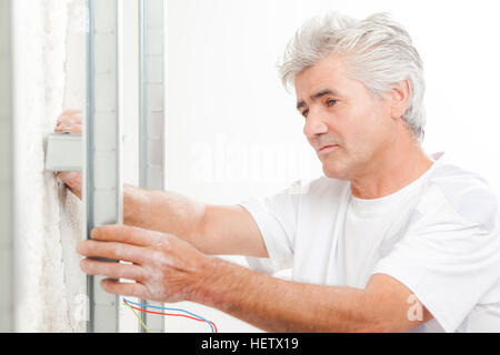 Builder measuring distance of framework from wall Stock Photo