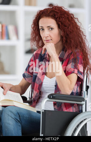 disabilty and handicap young disabled woman on wheelchair reads book