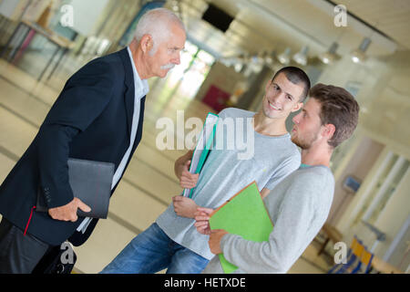 Students talking to teacher in lobby Stock Photo