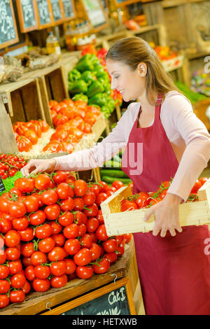Shop assistant restocking pile of tomatoes Stock Photo
