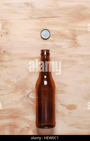 Empty beer bottle and a cown cap on a textured wooden surface Stock Photo