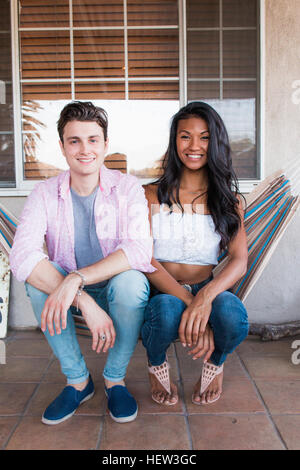 Portrait of young couple relaxing on veranda, sitting on hammock Stock Photo