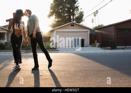 Young couple outdoors, kissing, young woman holding guitar Stock Photo