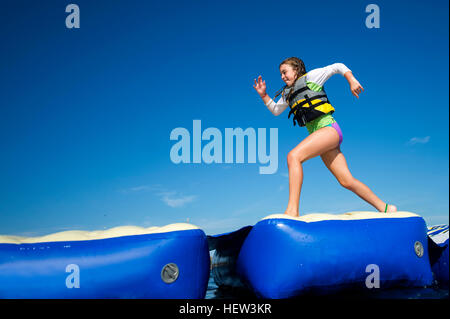 Girl running across inflatable platforms, Seaside Heights, New Jersey, USA Stock Photo